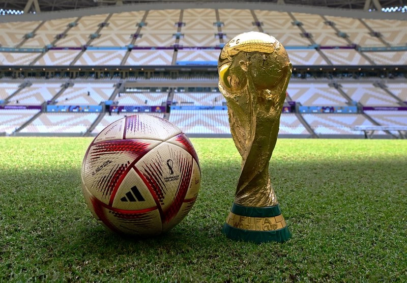 Pelota adidas Al Hilm junto al trofeo de la Copa del mundo de fútbol